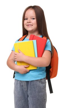 Beyaz arka planda defterleri ve sırt çantası olan sevimli küçük bir kız.