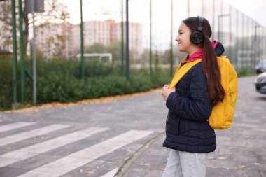 Kulaklıklı küçük bir kız yaya geçidinde yürüyor dışarıda, mesaj için yer var. Çocuk tehlikede ve yol güvenliği