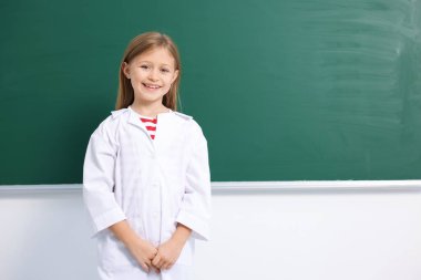 Yeşil karatahtanın yanında laboratuvar önlüklü gülümseyen küçük kız, mesaj için yer var. Çocuk ve bilim