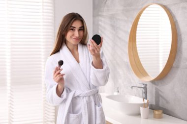 Bornozlu, yüz pudralı ve kapalı mekanlı güzel bir kadın.