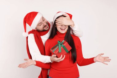 Mutlu adam beyaz arka planda Noel hediyesiyle sevgilisine sürpriz yapıyor.