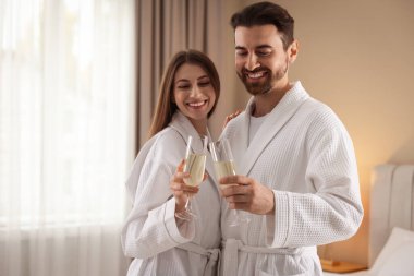 İçeride köpüklü şarap bardakları olan bornozlu mutlu bir çift. Metin için boşluk