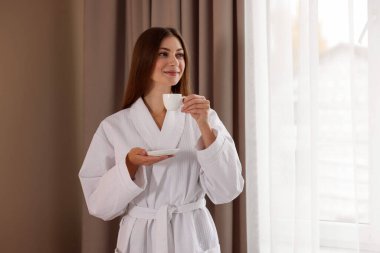 Bornozlu güzel bir kadın, pencerenin yanında sabah kahvesi var. Metin için boşluk
