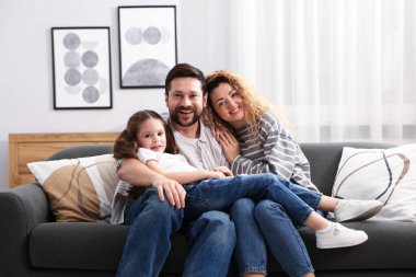 Mutlu ebeveynler ve kızları evdeki kanepede. Aile bağı