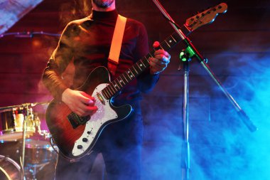Sahnede elektro gitar çalan adam dumanlı, yakın plan