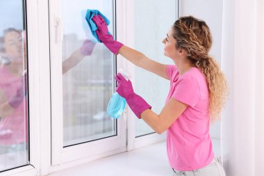 Camları paçavra ve deterjanla temizleyen kadın.