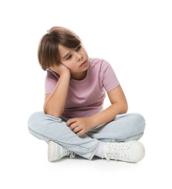 Üzgün küçük çocuk beyaz arka planda oturuyor.