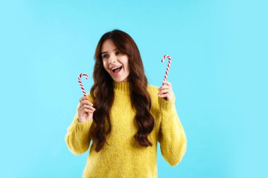 Açık mavi arka planda şeker kamışlı genç bir kadın. Mutlu Noeller ve mutlu yıllar.