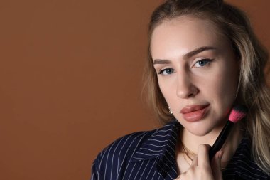 Kahverengi arka planda fırçası olan makyaj sanatçısı, yakın plan. Metin için boşluk