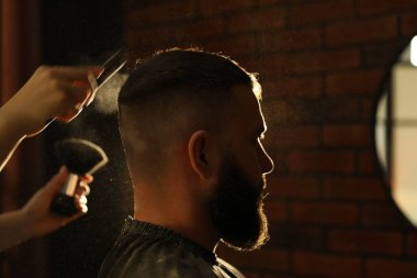 Kuaför, kuaförde saç fırçasıyla talk pudrası uyguluyor.