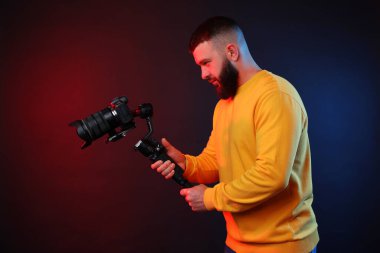 Kamerada çekim yapan kameraman, koyu arkaplandaki renk ışıklarına karşı titreşim dengeleyici kullanıyor.