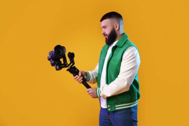 Sarı zemin üzerinde kamera olan titreşimli dengeleyici kullanan kameraman