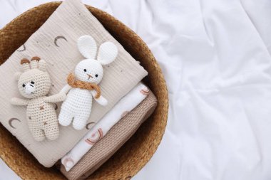 Çamaşır sepetinde katlanmış giysiler ve çarşafların üzerinde oyuncaklar, üst manzara. Metin için boşluk