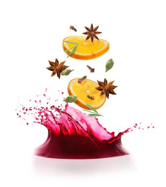 Sıcak şarap sıçratır ve beyaz arka planda düşen baharatlar