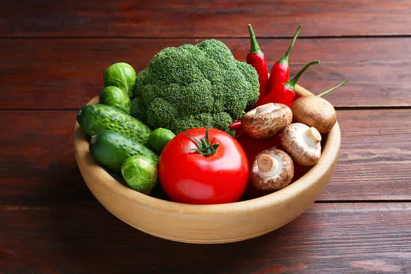 Tahta masadaki kasede farklı taze taze sebzeler, yakın plan.