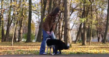 Sonbahar parkında sevimli köpeğini gezdiren bir kadın.