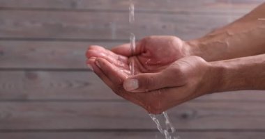 Ahşap zemine karşı insanın ellerine su dökmek, yakın plan