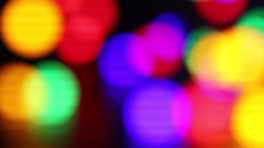 Karanlık arka planda parlayan parlak Noel ışıkları, bokeh etkisi. Kamera sağa hareket ediyor