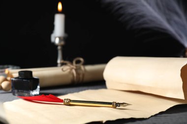 Eski kağıt parşömenler, dolmakalem, mürekkep hokkası ve yanan mum gri ahşap masa, seçici odak