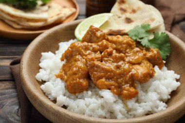 Pirinçli tavuk tikka masala, kişniş, kireç ve lavaş ahşap masada, yakın plan.