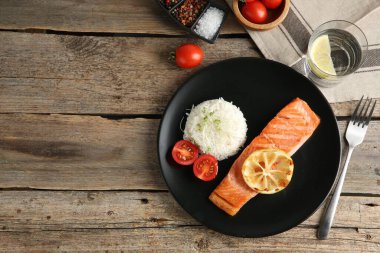 Ahşap masada servis edilen lezzetli ızgara somon ve pilav. Metin için boşluk