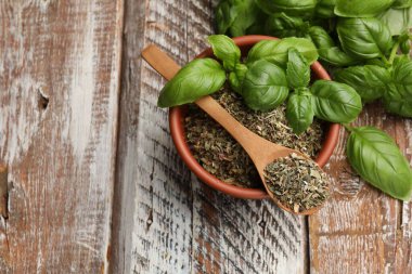 Kuru fesleğen yaprakları ve taze olanlar renkli ahşap masada, düz yerde. Metin için boşluk