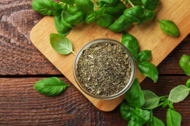 Kuru fesleğen yaprakları ve taze yapraklar ahşap masada, düz yatıyordu.