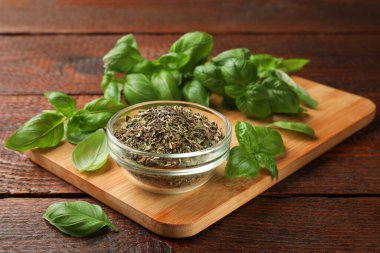 Kuru fesleğen yaprakları, taze olanlar ve ahşap masaya kase, yakın plan.