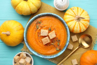 Tohumlu ve kızarmış ekmekli lezzetli balkabağı kremalı çorba açık mavi ahşap masa, düz yatıyordu.