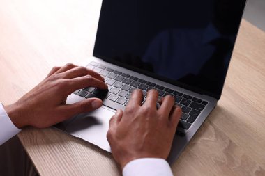Tahta masada dizüstü bilgisayar kullanan Afro-Amerikalı bir adam.