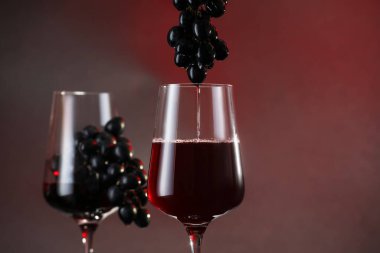 Kırmızı şarabı, arka plandaki üzümlerin arasından cama dök.