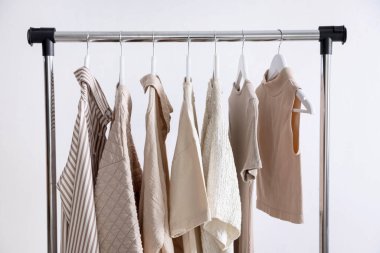 Farklı kadın kıyafetleri arka planda asılı duruyor.