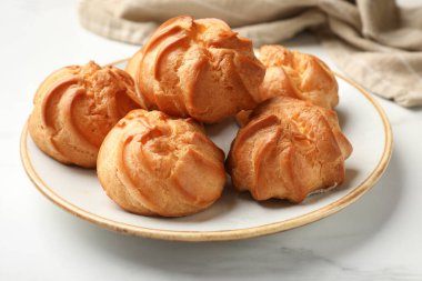 Taze lezzetli profiteroller beyaz mermer masada, yakın plan.