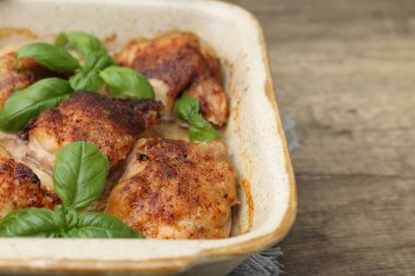 Ahşap masada fesleğenle pişirilmiş tavuk butları, yakın plan. Metin için boşluk
