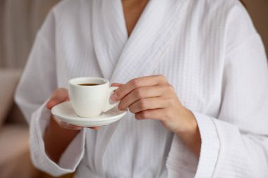 Bornozlu kadın, sabah kahvesi içeride, yakın plan.