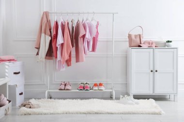 Askıda asılı farklı şık kıyafetler, aksesuarlar ve ayakkabılar.