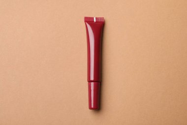 Kahverengi arkaplanda güzel kırmızı dudak parlatıcısı, üst manzara