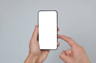 Gri arkaplanda boş ekranlı akıllı telefonu tutan adam, yakın plan.