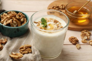 Delicious Greek yogurt with honey and walnuts served on white wooden table, closeup