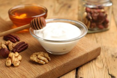 Ahşap masada bal ve fındıklı lezzetli Yunan yoğurdu, yakın plan.