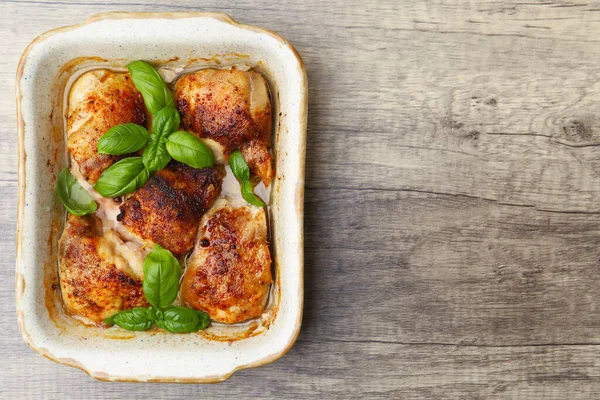 Ahşap masada fesleğenle pişirilmiş tavuk butları, üst manzara. Metin için boşluk