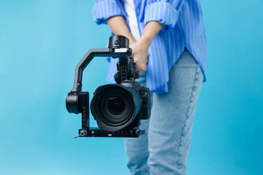 Açık mavi arkaplanda kamerası olan titreşimli dengeleyici kullanan kameraman, kapat