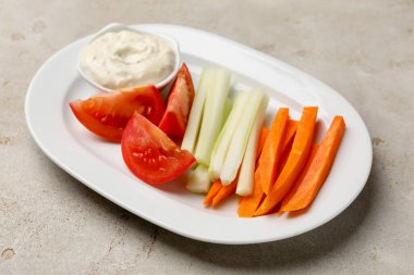 Açık gri masada farklı taze sebzeler ve sos, yakın plan.