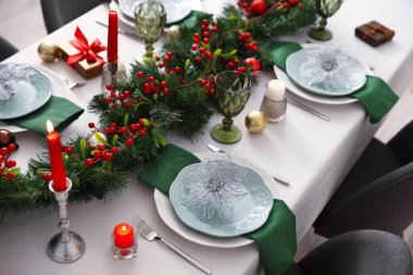 Noel dekorlu şenlik masası ve kapalı mekanda yanan mumlar.