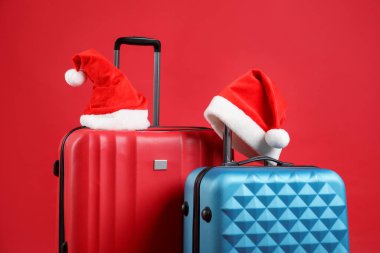 Noel tatili. Kırmızı arka planda Noel Baba şapkalı bavullar