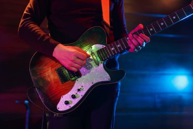 Sahnede elektro gitar çalan adam, yakın plan.