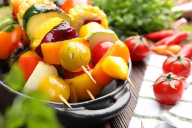 Ahşap masada lezzetli ızgara sebzeli şişler, yakın plan.