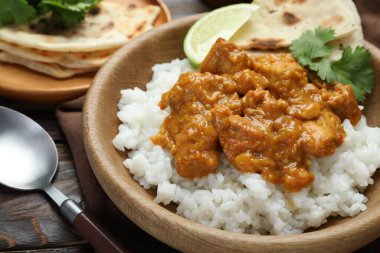 Pirinçli tavuk tikka masala, kişniş, kireç ve lavaş ahşap masada, yakın plan.