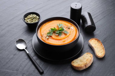 Gri masada servis edilen maydanozlu balkabağı kremalı çorba.