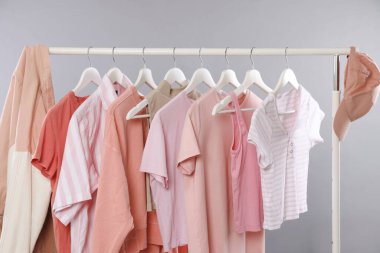 Gri arkaplanda asılı duran farklı şık kıyafetler, yakın plan.